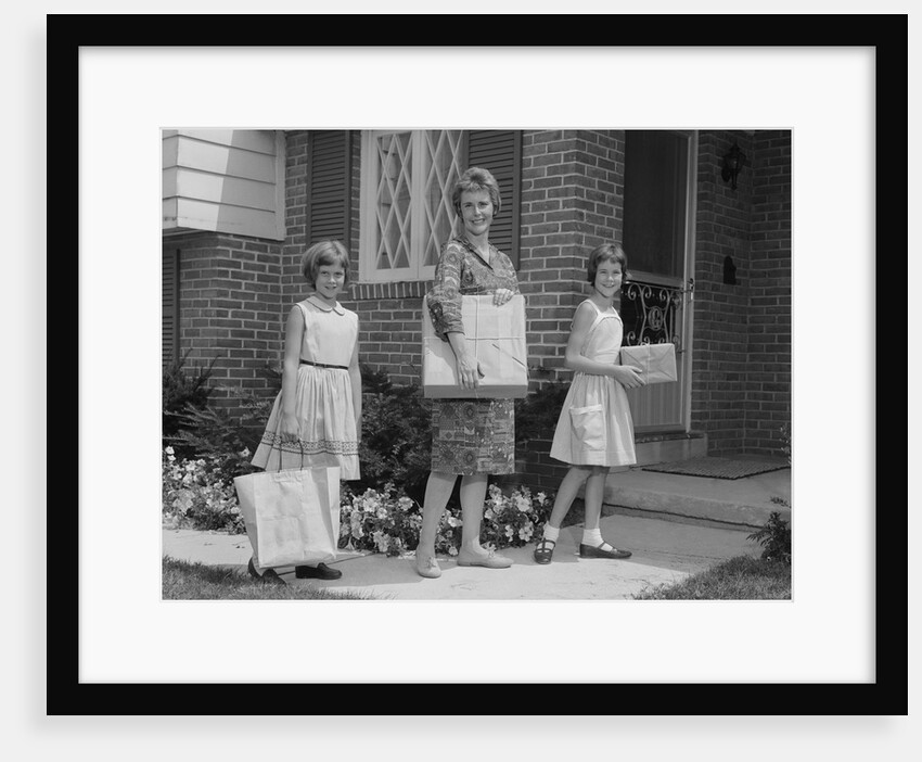 Mother and two daughters carrying shopping bags packages into house by Anonymous