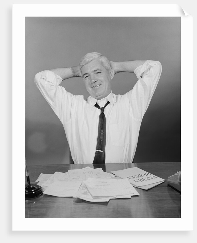 Smiling man working on family budget papers at desk by Anonymous