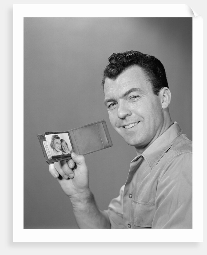 Smiling man holding up wallet with picture of wife and daughter by Anonymous
