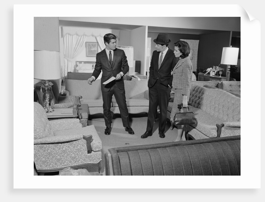 Furniture store salesman talking to couple by Anonymous