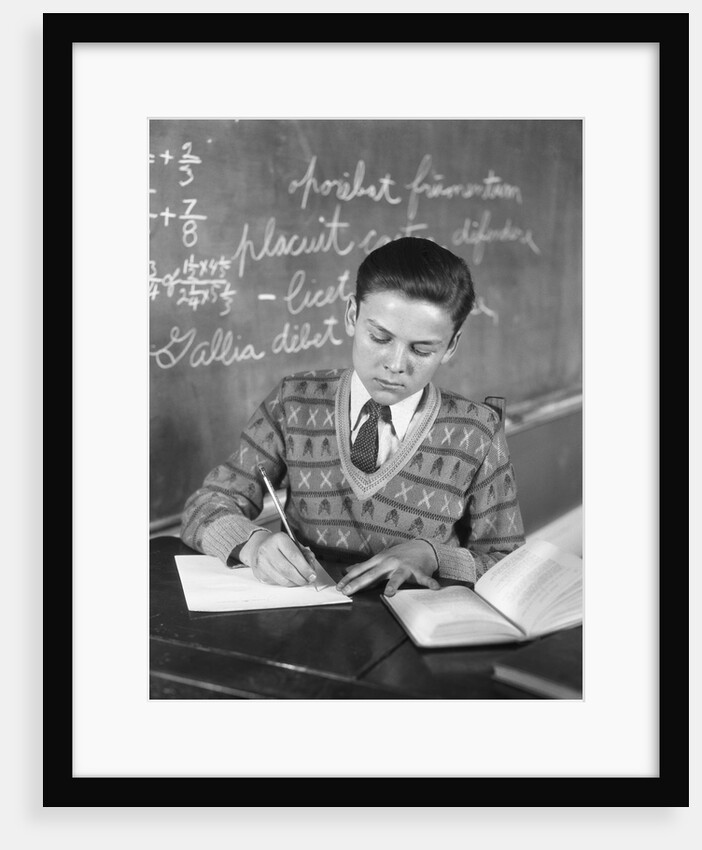 Boy vee neck sweater writing at school desk by Anonymous