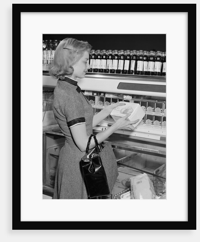 Blond woman selecting ice cream frozen food section supermarket by Anonymous