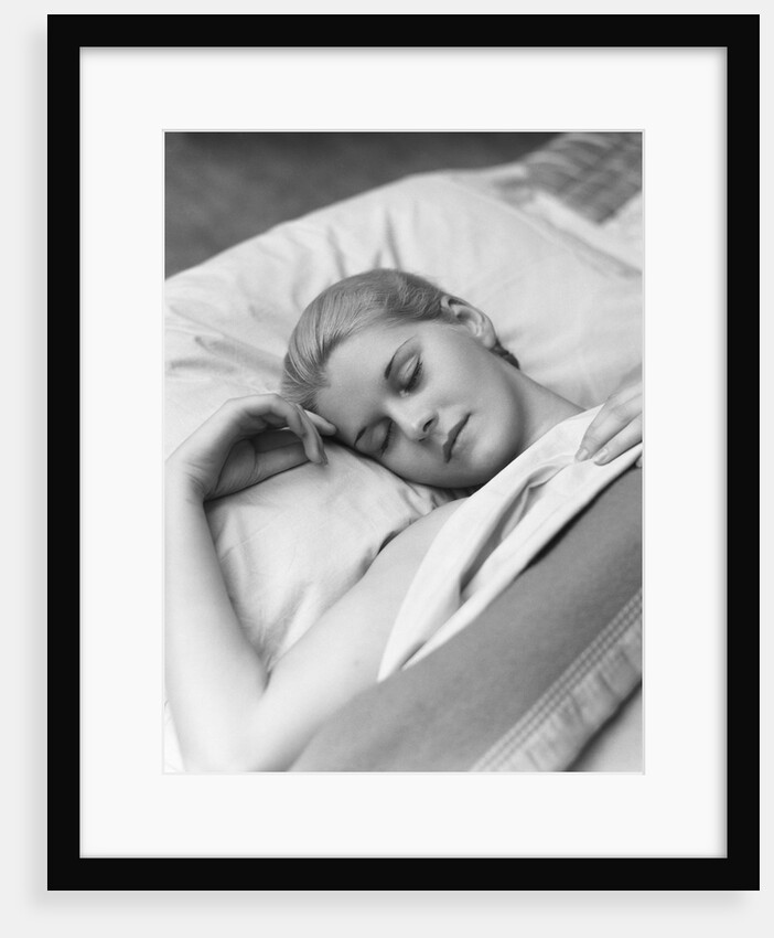 Sleeping blond woman eyes closed head resting on pillow in bed by Anonymous