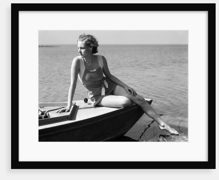 Woman wearing one piece bathing suit sitting on edge of boat by Anonymous