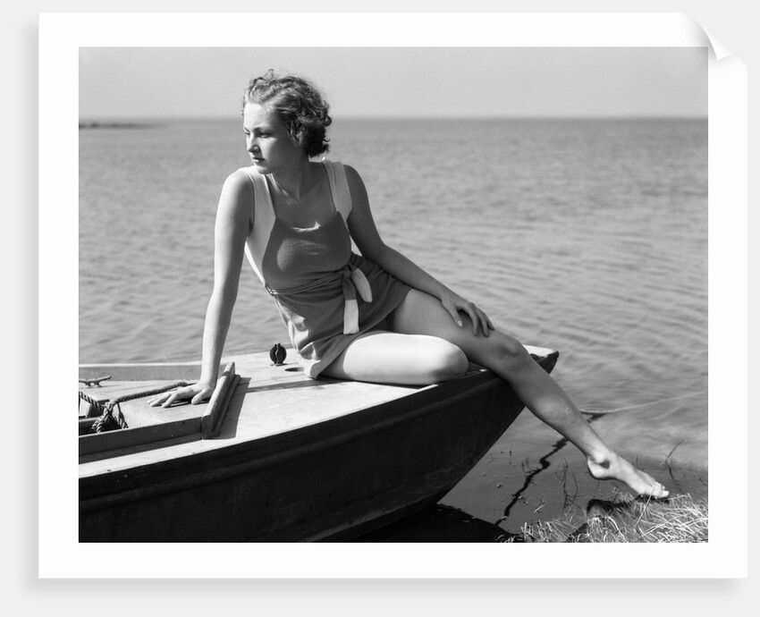Woman wearing one piece bathing suit sitting on edge of boat by Anonymous