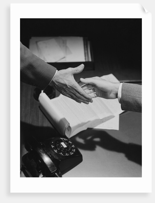 Close-up two male hands about to shake over desk with papers and telephone by Anonymous