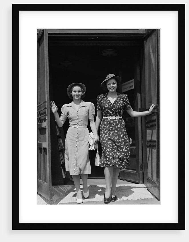 Two smiling women walking out doorway of a store by Anonymous