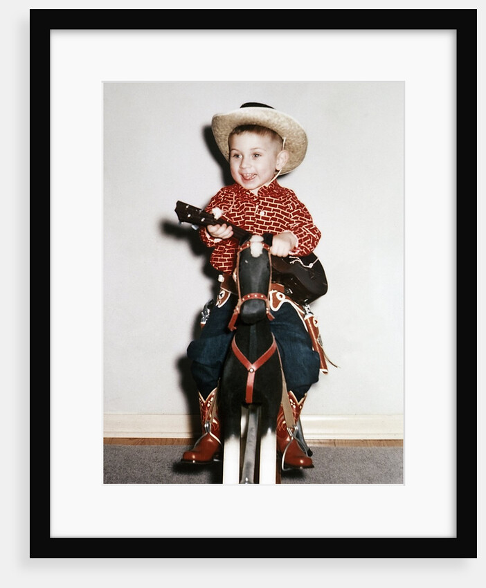 Little boy cowboy plays guitar while riding his horse, ca. 1956 by Anonymous