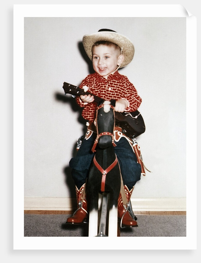 Little boy cowboy plays guitar while riding his horse, ca. 1956 by Anonymous