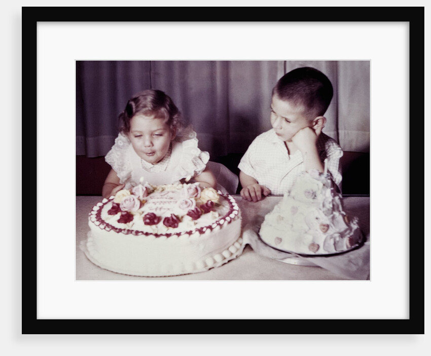 Brother watches his sister blow out candles on birthday cake, ca. 1956 by Anonymous