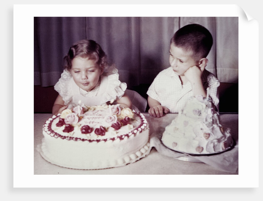 Brother watches his sister blow out candles on birthday cake, ca. 1956 by Anonymous