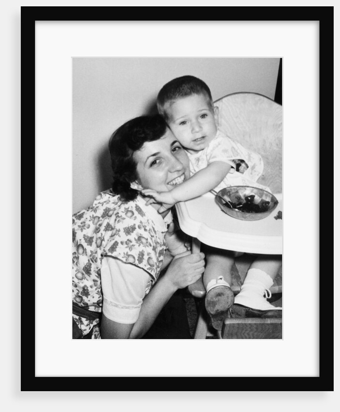 Baby boy hugging mother at dinner time, ca. 1953 by Anonymous