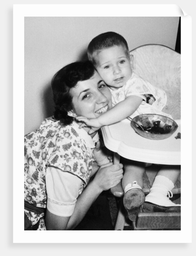 Baby boy hugging mother at dinner time, ca. 1953 by Anonymous