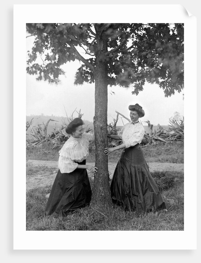 Two women chase each other around a tree, ca. 1910 by Anonymous