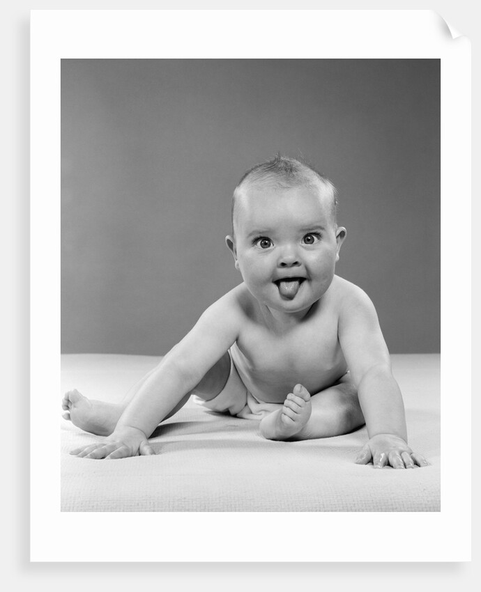 1950s portrait of baby sitting and sticking tongue out looking at camera by Anonymous