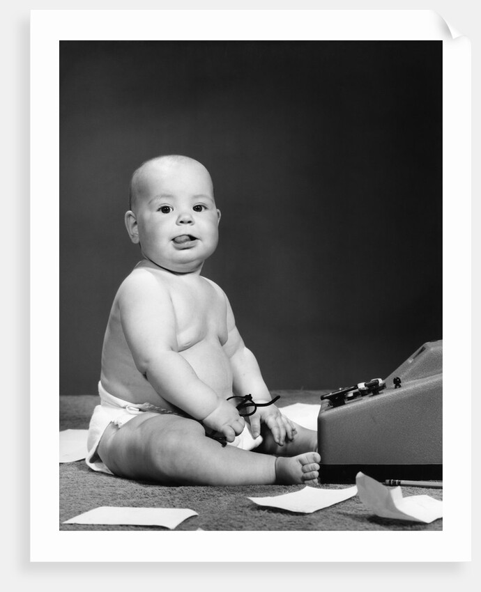 1950s 1960s baby in diaper sticking out tongue holding glasses sitting before adding machine looking at camera by Anonymous