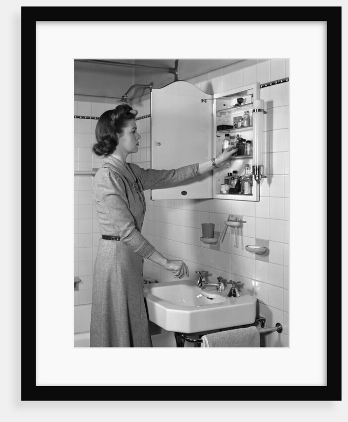 1940s woman reaching into bathroom medicine cabinet by Anonymous