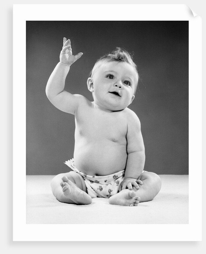 1950s portrait of baby sitting one arm raised waving by Anonymous