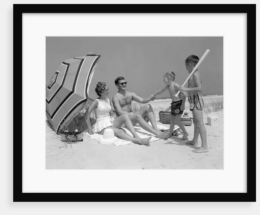 1960s at the beach two boys with baseball bat trying to pull up father seated next to mother so he will play with them by Anonymous