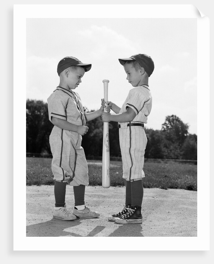 1960s two boys in baseball uniforms choosing sides by getting the upper hand on a bat by Anonymous