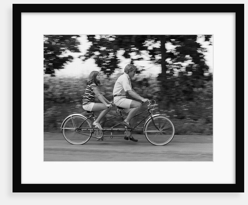 1970s teenage girl and boy riding bicycle built for two by Anonymous