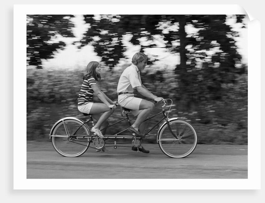 1970s teenage girl and boy riding bicycle built for two by Anonymous