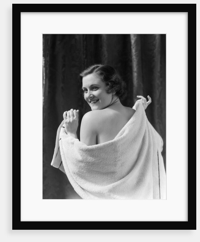 1930s smiling brunette woman looking over shoulder drying back with towel looking at camera by Anonymous