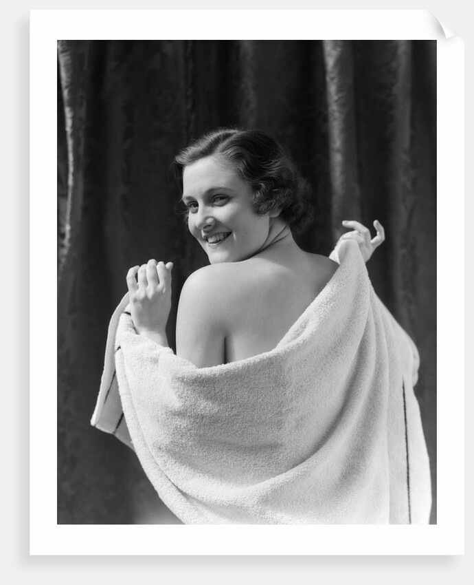 1930s smiling brunette woman looking over shoulder drying back with towel looking at camera by Anonymous
