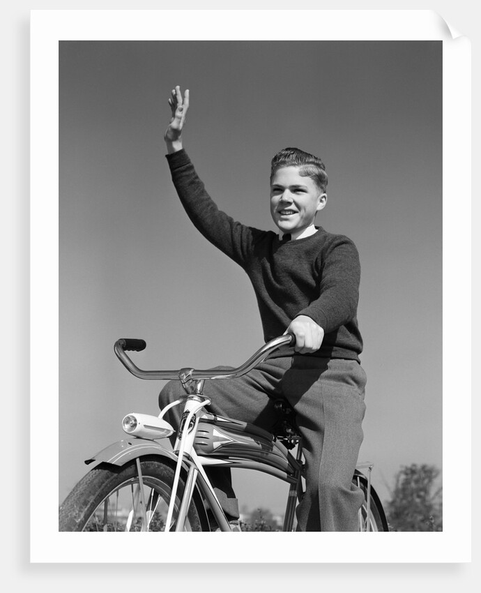 1940s 1950s smiling boy riding bike waving arm in air by Anonymous