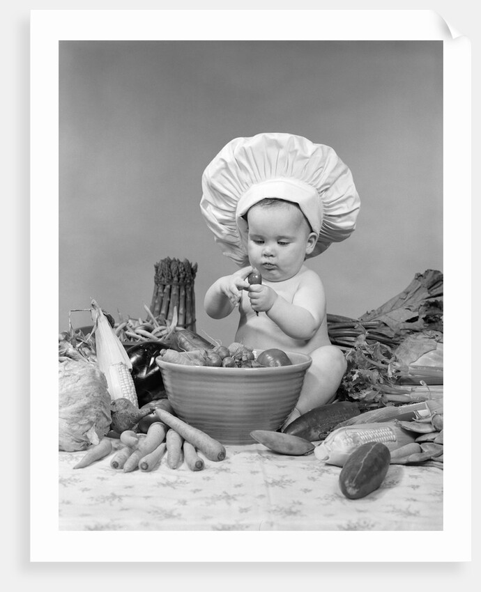 1950s 1960s baby wearing chef hat toque bowl and raw vegetables making a salad by Anonymous