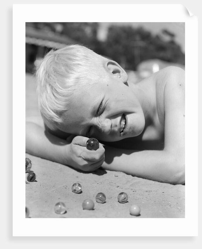 Boy crouching shooting marbles concentration by Anonymous