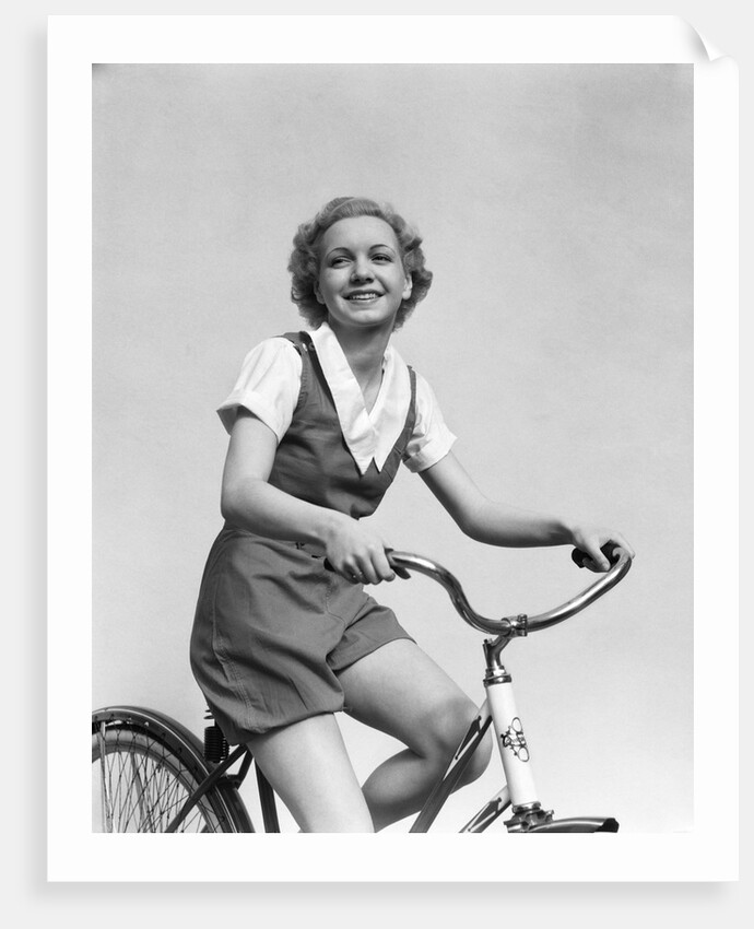 1930s smiling blonde woman riding bicycle looking at camera by Anonymous