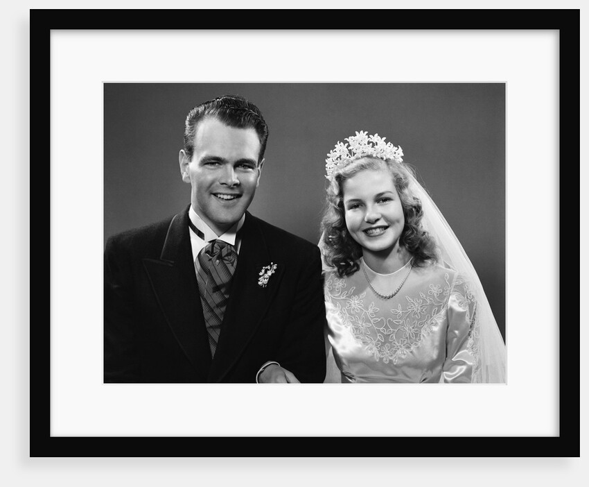 1940s portrait of bride and groom linked arm in arm looking at camera by Anonymous