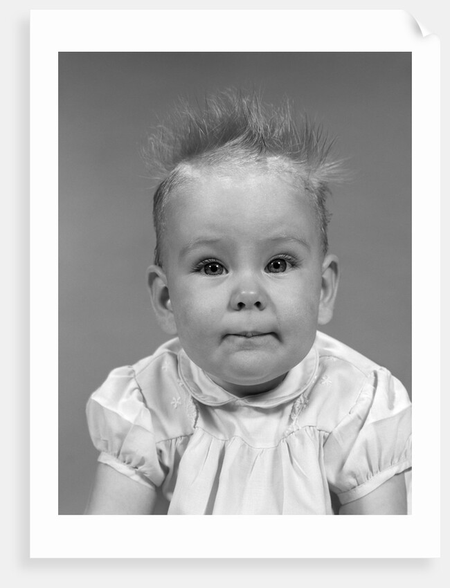 1960s head on portrait of baby girl in ruffled dress straight up hair looking at camera by Anonymous