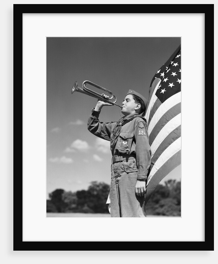 1950s profile of boy scout in uniform standing in front of 48 star american flag blowing bugle by Anonymous