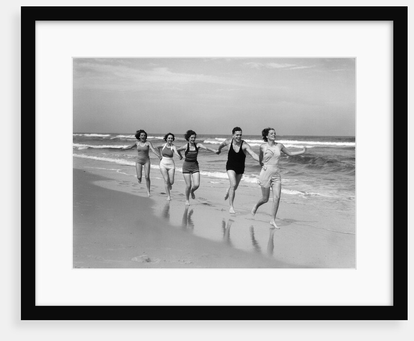 1930s four women and one man running on beach holding hands by Anonymous