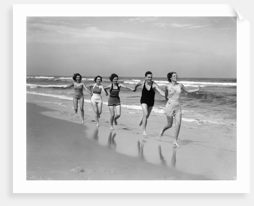 1930s four women and one man running on beach holding hands by Anonymous