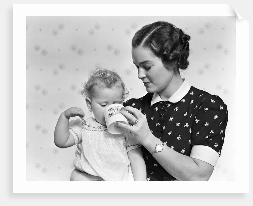 1930s woman mother giving baby daughter drink from mug by Anonymous