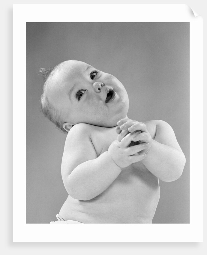 1950s baby in diaper head to one side arms hands clasped in front by Anonymous