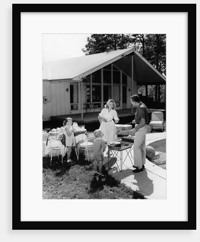 1950s family grilling hamburgers beside pool in backyard cookout by Anonymous