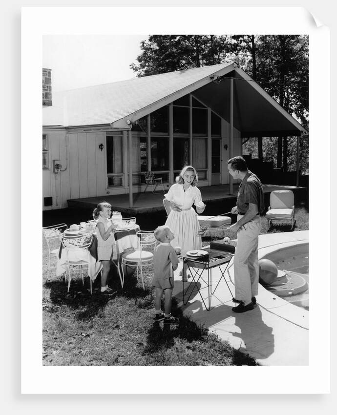 1950s family grilling hamburgers beside pool in backyard cookout by Anonymous