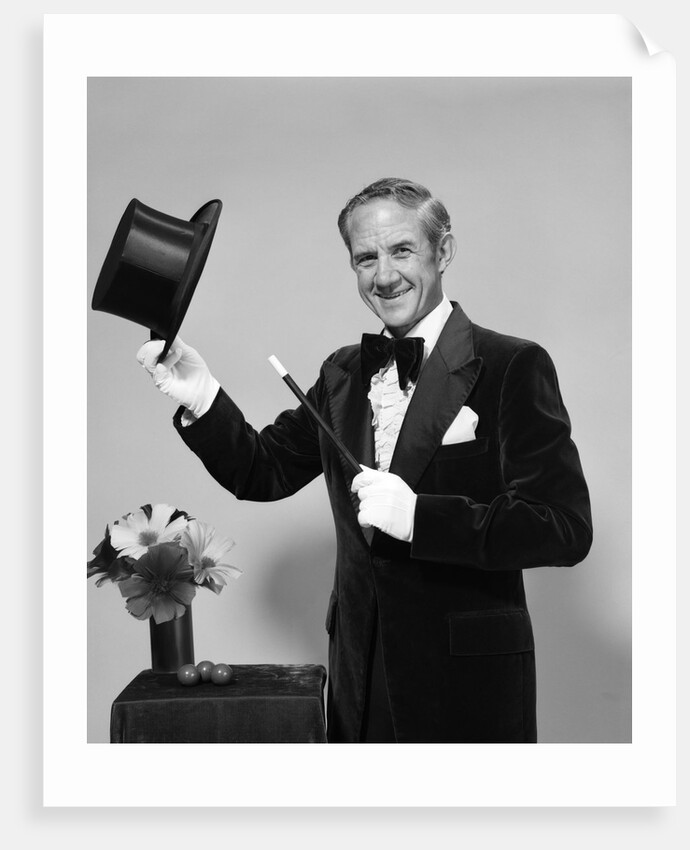 1970s smiling man magician wearing velvet tuxedo white gloves pointing magic wand at top hat looking at camera by Anonymous