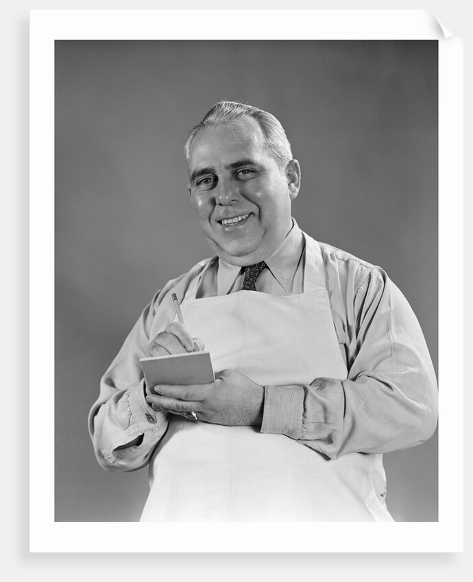 1940s man wearing white apron writing order on pad with pencil looking at camera by Anonymous