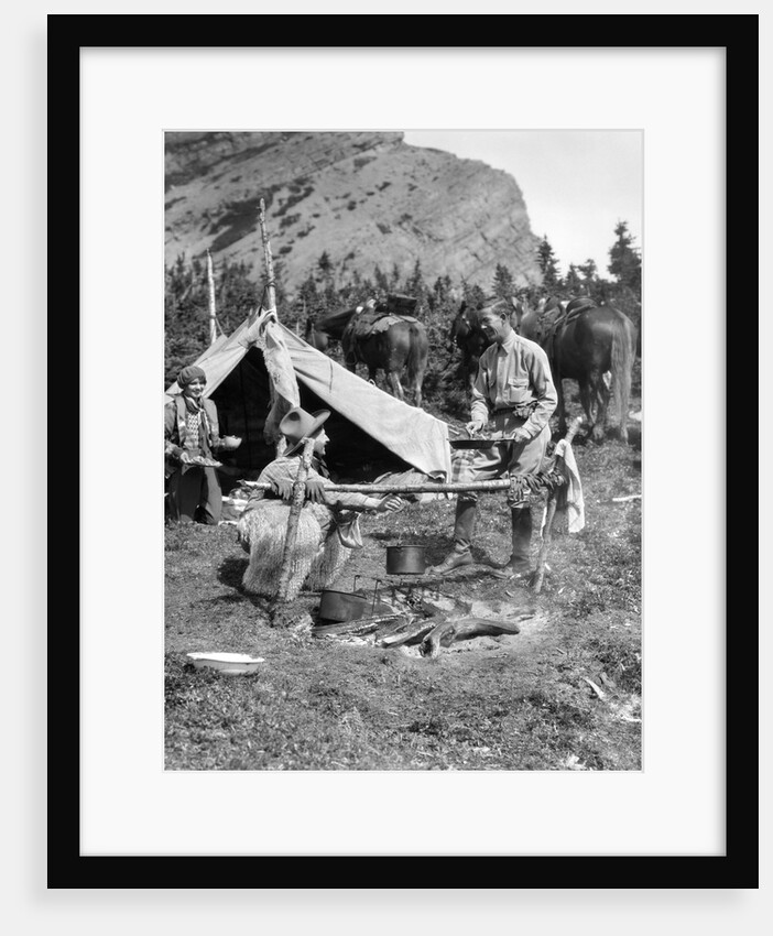 1920s 1930s two men and one woman eating a meal around a campfire with a tent and horses at baker lake alberta canada by Anonymous