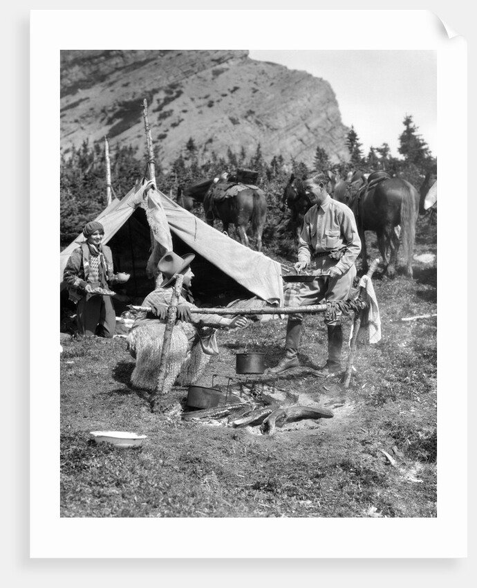 1920s 1930s two men and one woman eating a meal around a campfire with a tent and horses at baker lake alberta canada by Anonymous