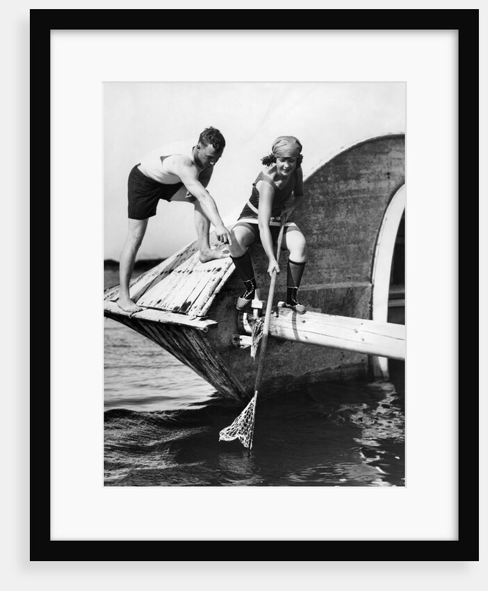 1920s man and woman in bathing suits crabbing off old abandoned wooden boat by Anonymous