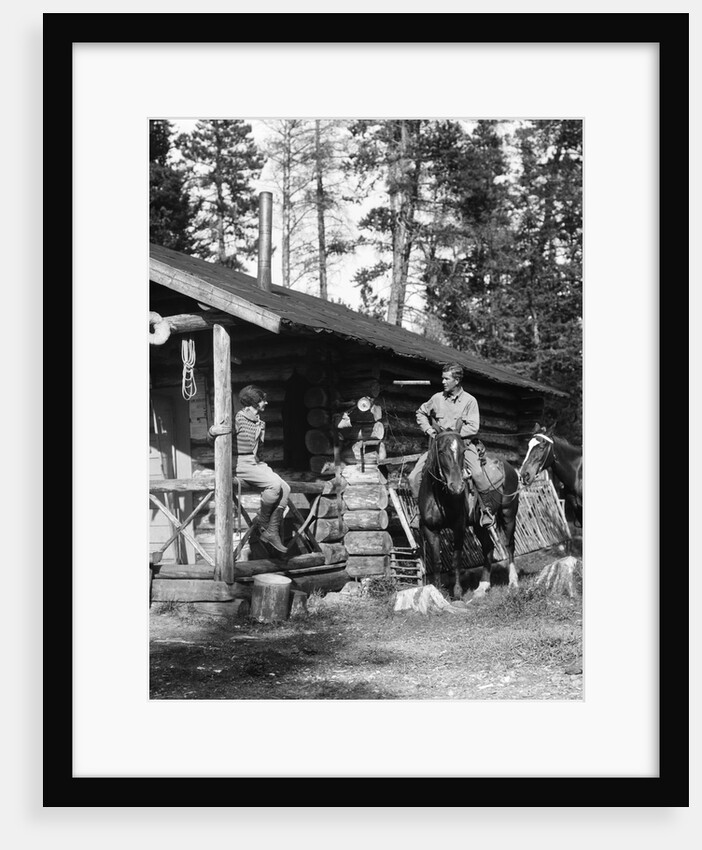1920s 1930s couple in front of log cabin woman sitting on porch railing man on horse alberta canada by Anonymous