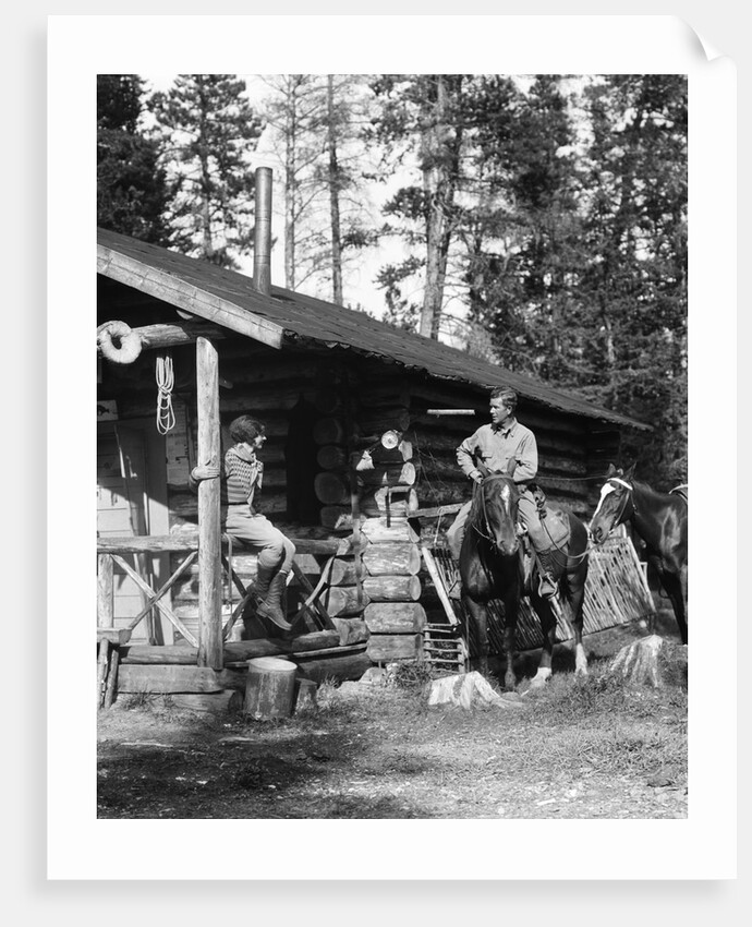 1920s 1930s couple in front of log cabin woman sitting on porch railing man on horse alberta canada by Anonymous