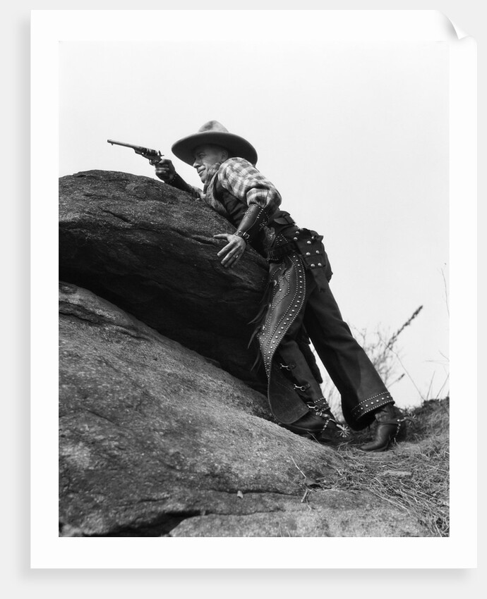 1920s cowboy among rocks aiming revolver by Anonymous