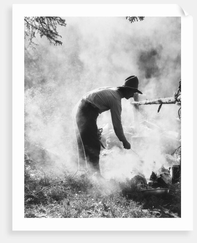 1920s 1930s man cowboy cook bending over campfire by Anonymous